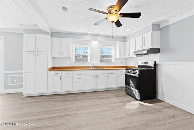 kitchen with wood counters, sink, a textured ceiling, stainless steel range with gas cooktop, and white cabinets