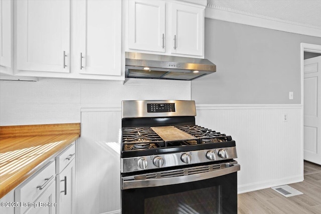 kitchen featuring wooden counters, stainless steel range with gas stovetop, white cabinets, and light hardwood / wood-style floors