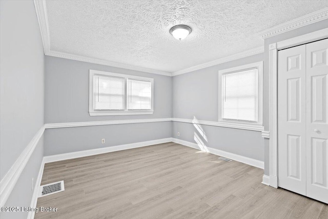 empty room with crown molding and light wood-type flooring