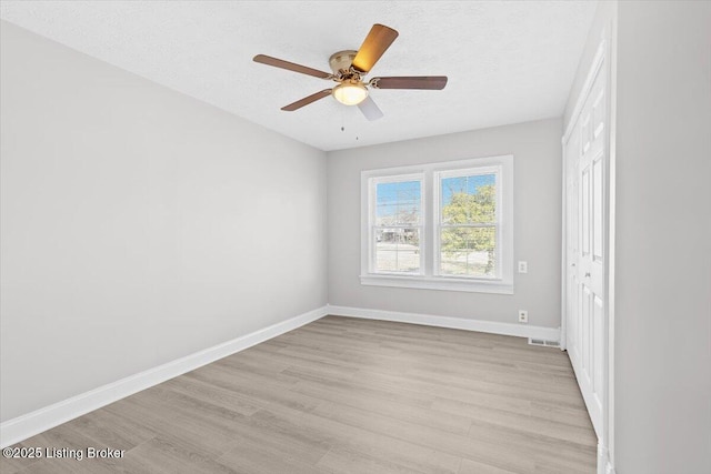 unfurnished room with ceiling fan, a textured ceiling, and light wood-type flooring