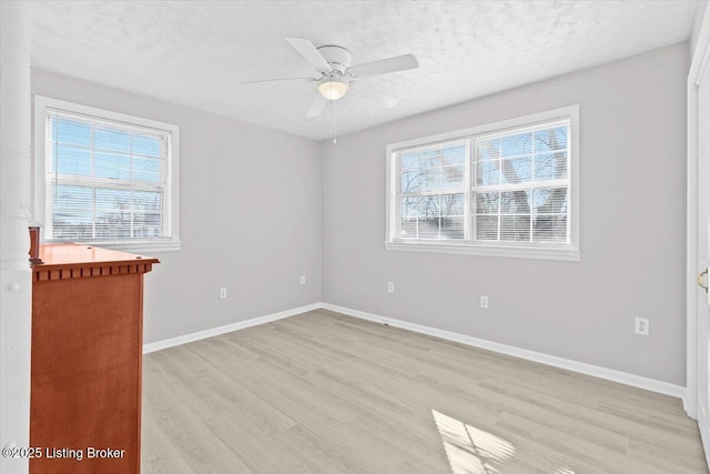 empty room featuring ceiling fan, a healthy amount of sunlight, a textured ceiling, and light wood-type flooring