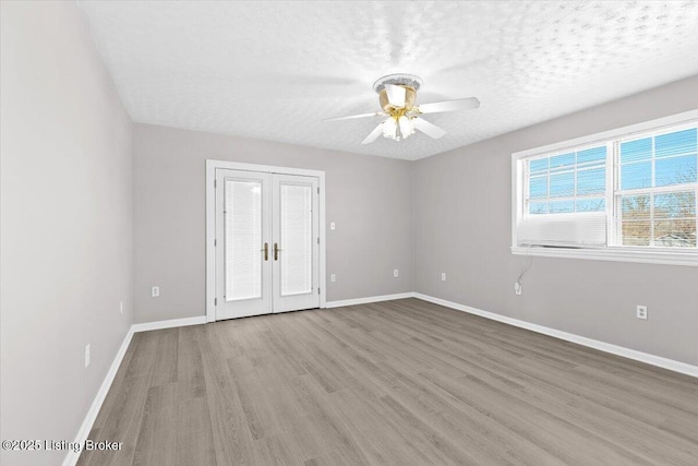 spare room featuring french doors, ceiling fan, a textured ceiling, and light hardwood / wood-style flooring