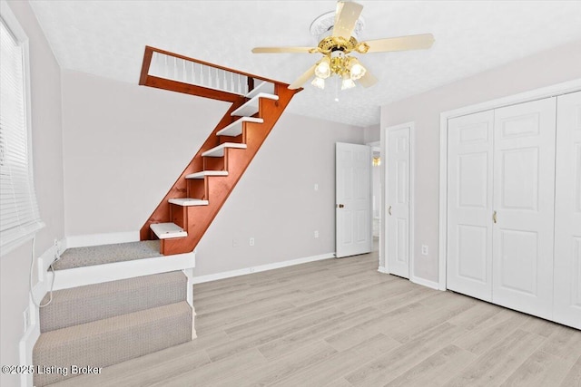 staircase with wood-type flooring and ceiling fan