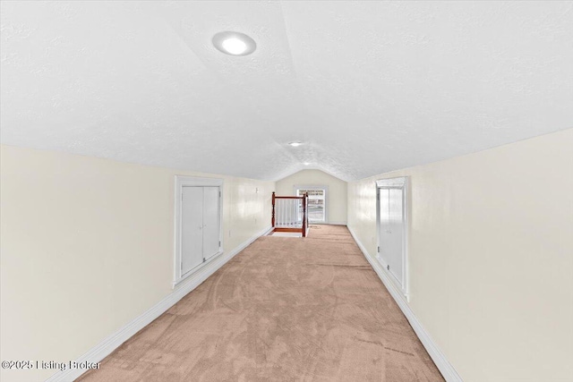 bonus room with vaulted ceiling, light colored carpet, and a textured ceiling