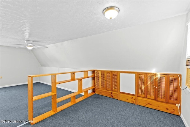 bonus room featuring vaulted ceiling, ceiling fan, dark carpet, and a textured ceiling