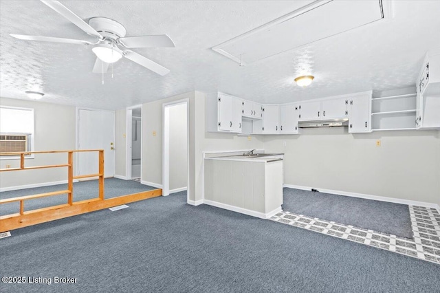 basement with cooling unit, ceiling fan, dark carpet, and a textured ceiling