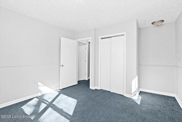 unfurnished bedroom featuring dark colored carpet, a textured ceiling, and a closet