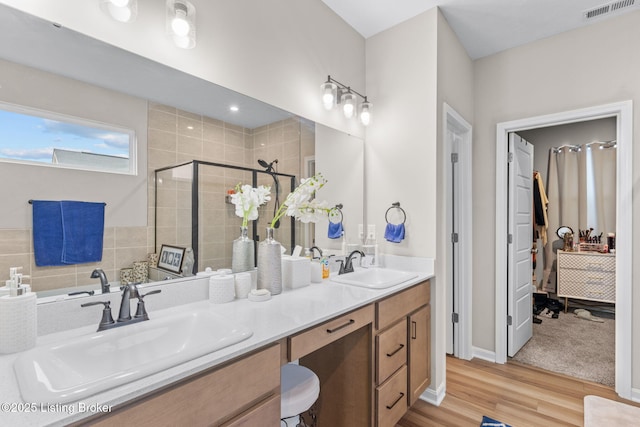 bathroom with hardwood / wood-style flooring, vanity, and a shower with door