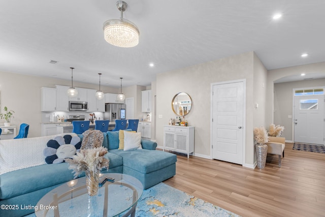 living room with an inviting chandelier and light wood-type flooring