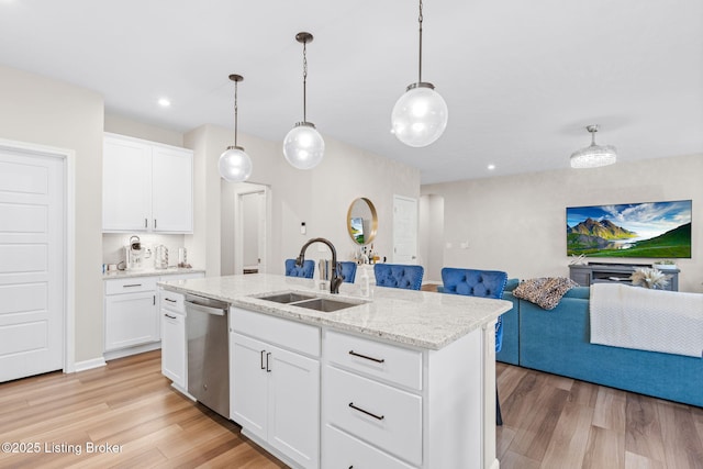 kitchen featuring sink, decorative light fixtures, dishwasher, a kitchen island with sink, and white cabinets