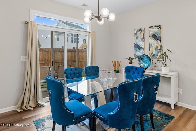 dining space with a notable chandelier and light hardwood / wood-style floors