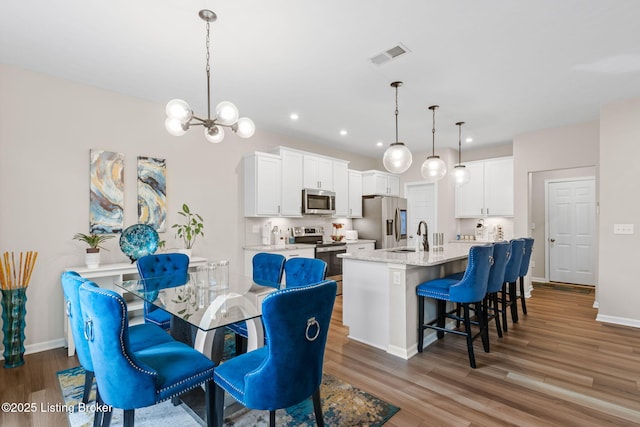 dining room featuring an inviting chandelier, sink, and dark hardwood / wood-style floors