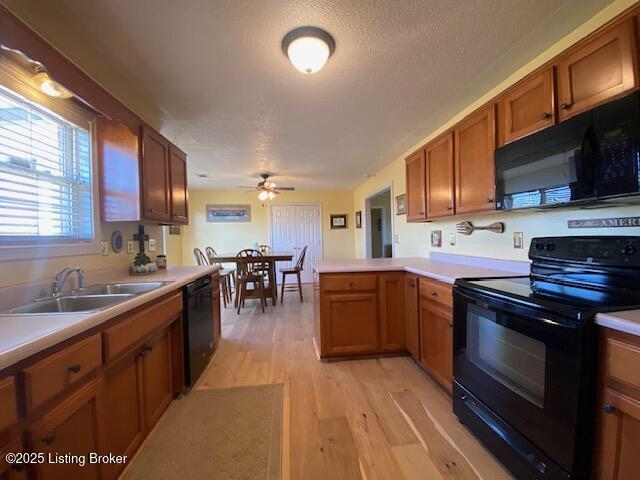 kitchen with sink, a textured ceiling, light wood-type flooring, kitchen peninsula, and black appliances