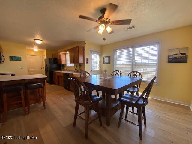 dining area featuring ceiling fan, light hardwood / wood-style flooring, and a textured ceiling