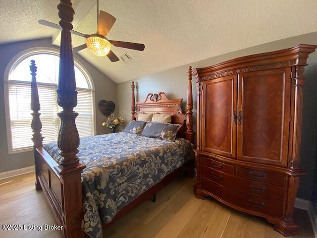 bedroom with vaulted ceiling, ceiling fan, light hardwood / wood-style floors, and a textured ceiling