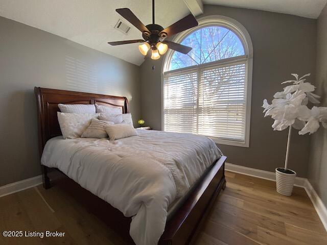 bedroom with multiple windows, lofted ceiling, dark wood-type flooring, and ceiling fan