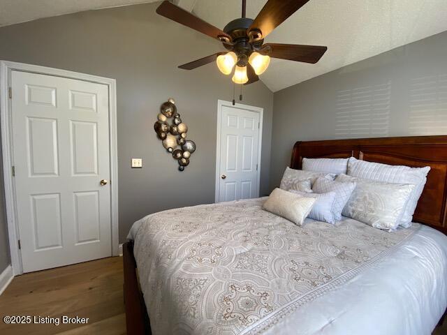 bedroom featuring hardwood / wood-style floors, vaulted ceiling, and ceiling fan