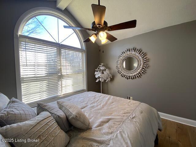 bedroom with ceiling fan, wood-type flooring, and vaulted ceiling with beams