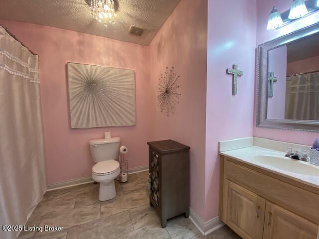 bathroom featuring vanity, a textured ceiling, and toilet