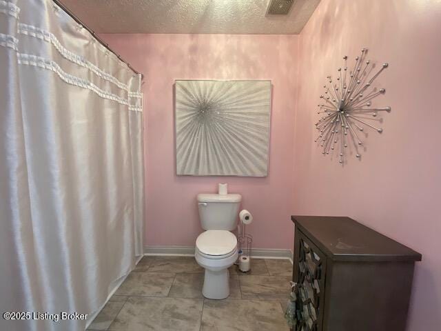 bathroom with tile patterned flooring, a textured ceiling, and toilet