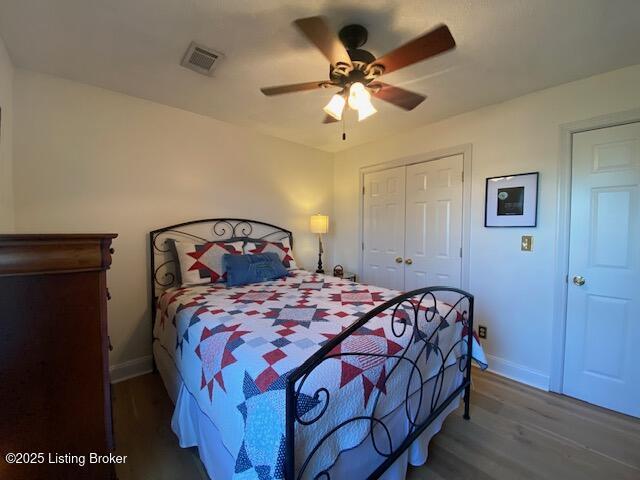 bedroom with ceiling fan, dark hardwood / wood-style flooring, and a closet