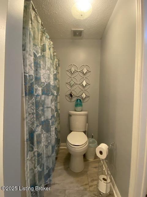 bathroom featuring a textured ceiling and toilet