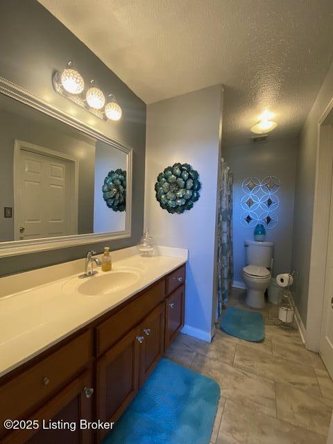 bathroom featuring vanity, a textured ceiling, and toilet