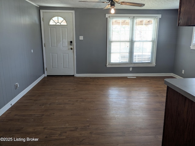 foyer with ceiling fan, dark wood-type flooring, and a textured ceiling