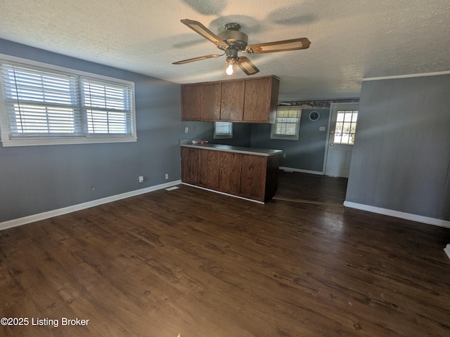 kitchen with dark wood-type flooring, a textured ceiling, ceiling fan, and kitchen peninsula