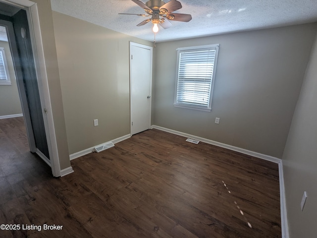 empty room featuring ceiling fan, dark hardwood / wood-style floors, and a textured ceiling