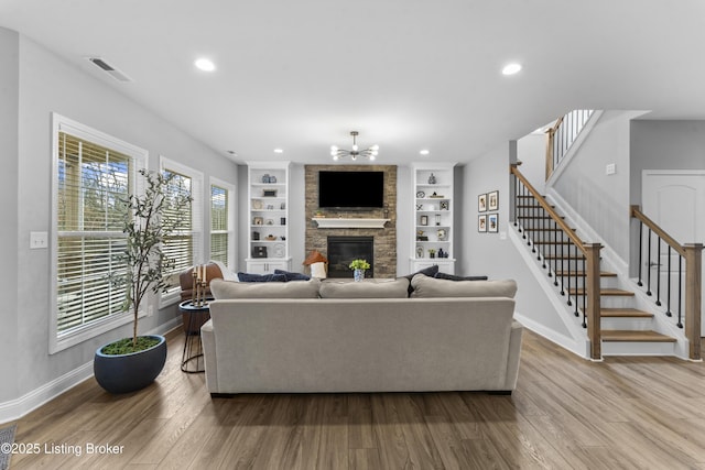 living room featuring a stone fireplace, built in features, and light wood-type flooring