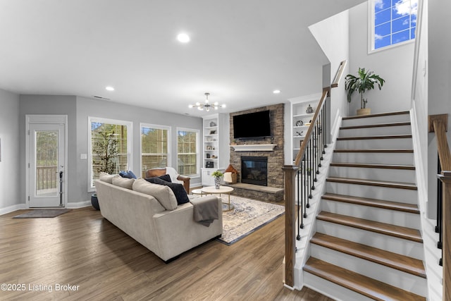 living room featuring hardwood / wood-style floors, a notable chandelier, a fireplace, and built in features