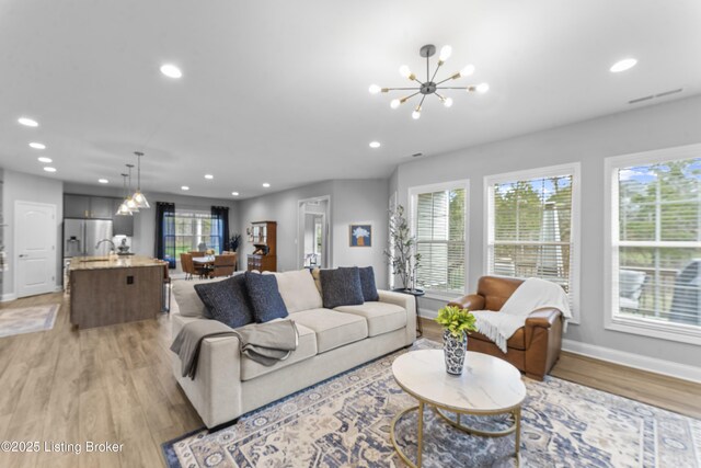 living room featuring a notable chandelier, plenty of natural light, and light wood-type flooring