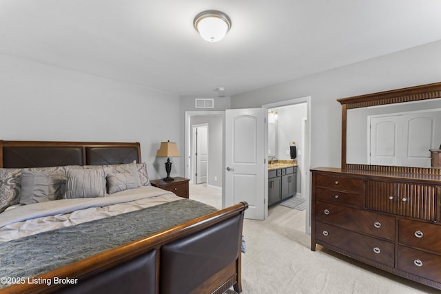 bedroom with light colored carpet and ensuite bathroom