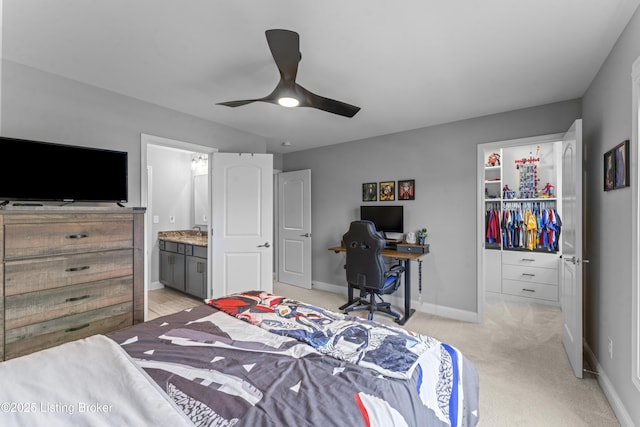 carpeted bedroom with a walk in closet, connected bathroom, and ceiling fan