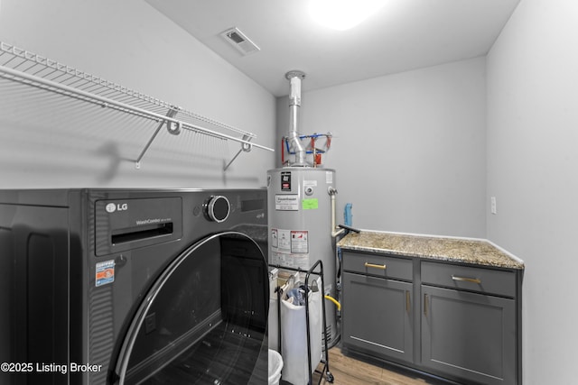 clothes washing area with cabinets, gas water heater, washer / dryer, and light wood-type flooring