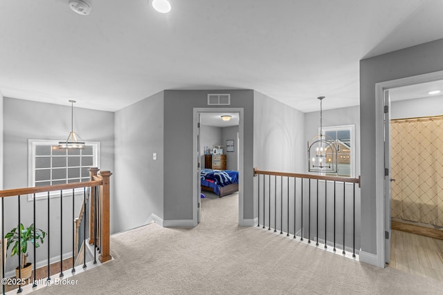 corridor with an inviting chandelier and carpet floors