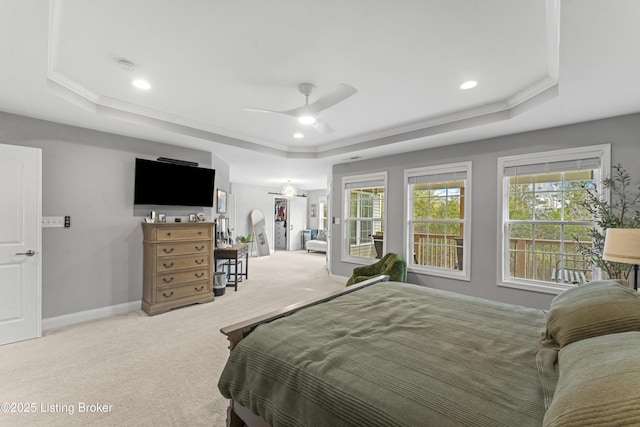 bedroom with a raised ceiling, light carpet, and multiple windows