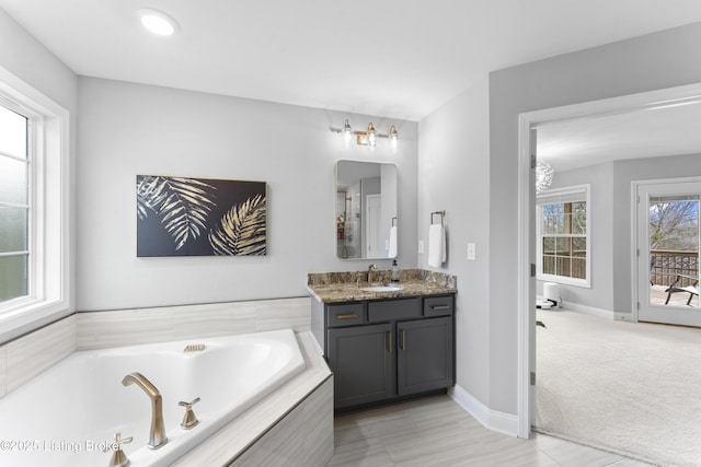 bathroom with vanity and tiled bath