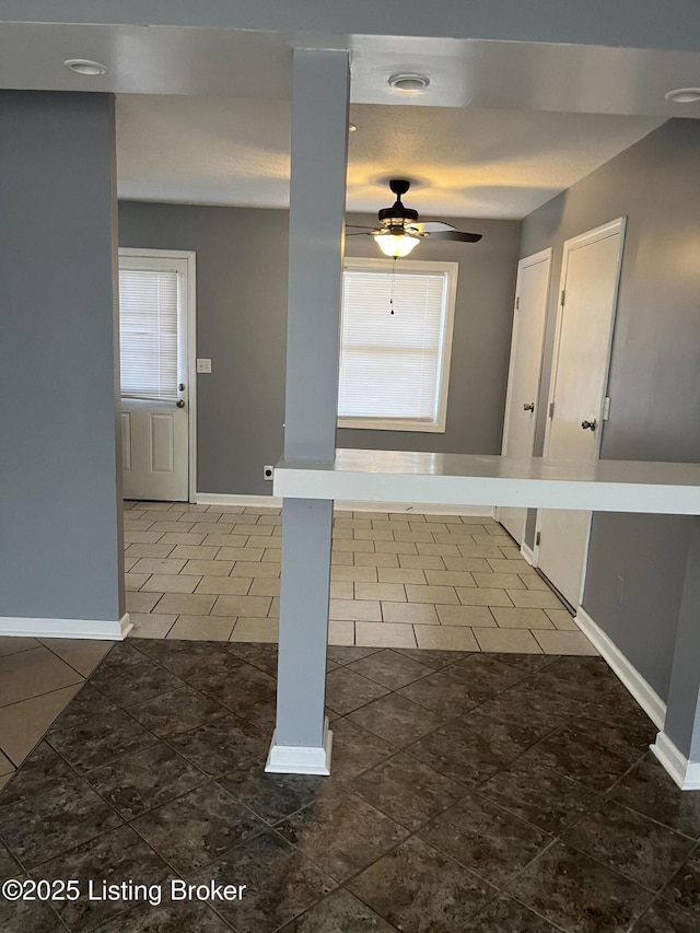 interior space featuring dark tile patterned flooring, a wealth of natural light, and ceiling fan