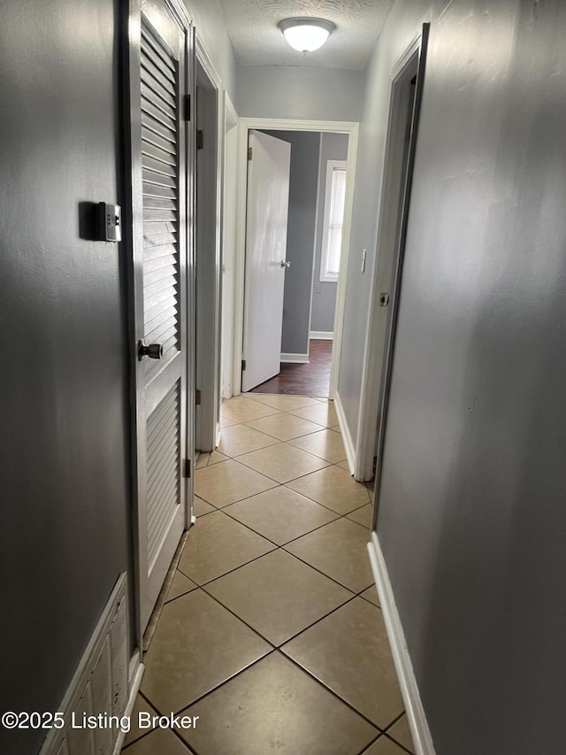 hall featuring light tile patterned flooring and a textured ceiling