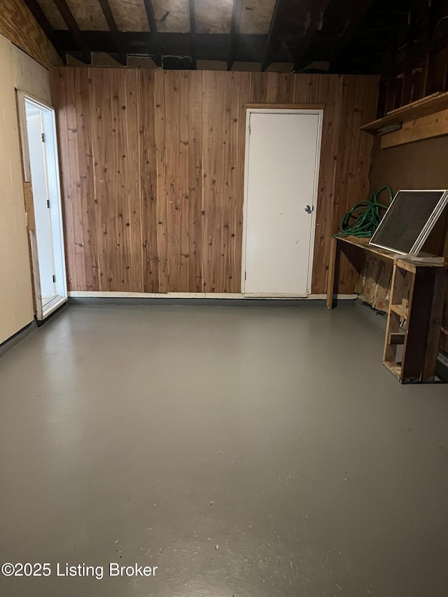 interior space featuring wooden walls and concrete floors