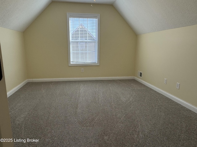 additional living space with carpet flooring, vaulted ceiling, and a textured ceiling