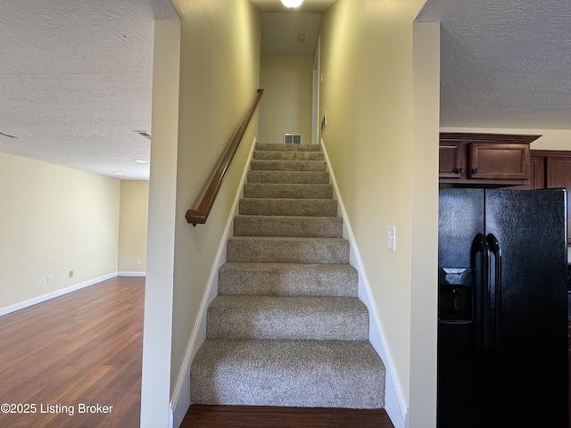 stairway with hardwood / wood-style floors and a textured ceiling