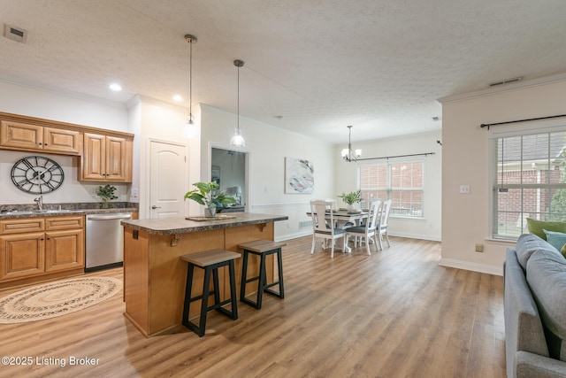 kitchen featuring a kitchen island, dishwasher, sink, a kitchen bar, and a textured ceiling