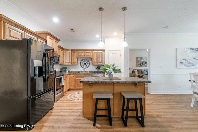 kitchen with black fridge, electric stove, light hardwood / wood-style floors, and a kitchen island