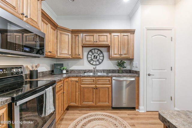 kitchen featuring crown molding, appliances with stainless steel finishes, sink, and light hardwood / wood-style flooring