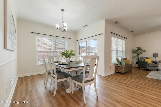 dining space with a notable chandelier, light hardwood / wood-style flooring, and ornamental molding