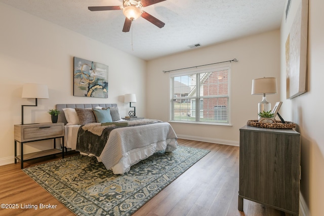 bedroom featuring hardwood / wood-style floors, a textured ceiling, and ceiling fan