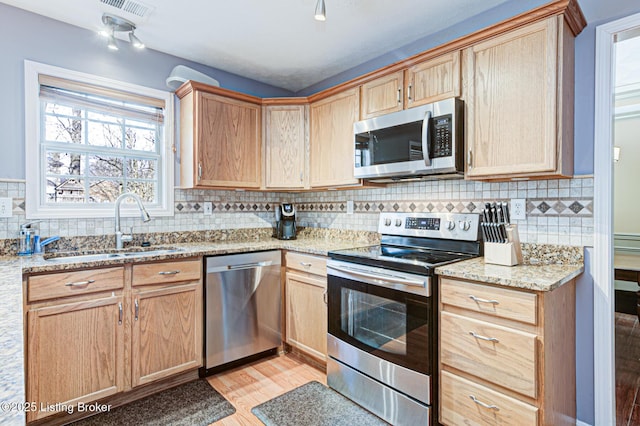 kitchen featuring sink, light hardwood / wood-style flooring, backsplash, stainless steel appliances, and light stone countertops